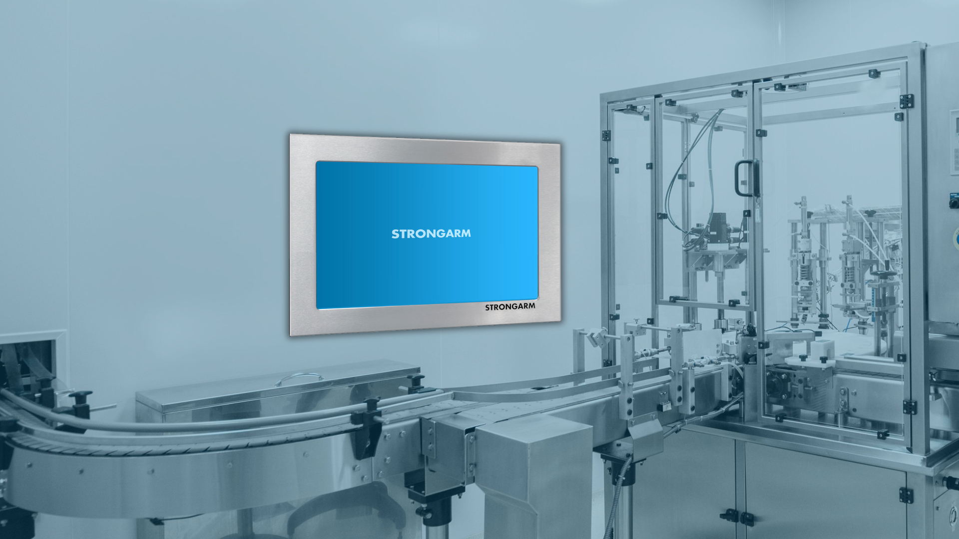Strongarm industrial panel PC mounted in a pharmaceutical manufacturing cleanroom, providing HMI and process control access alongside automated stainless steel production equipment and conveyor systems in a hygienic GMP-regulated environment.