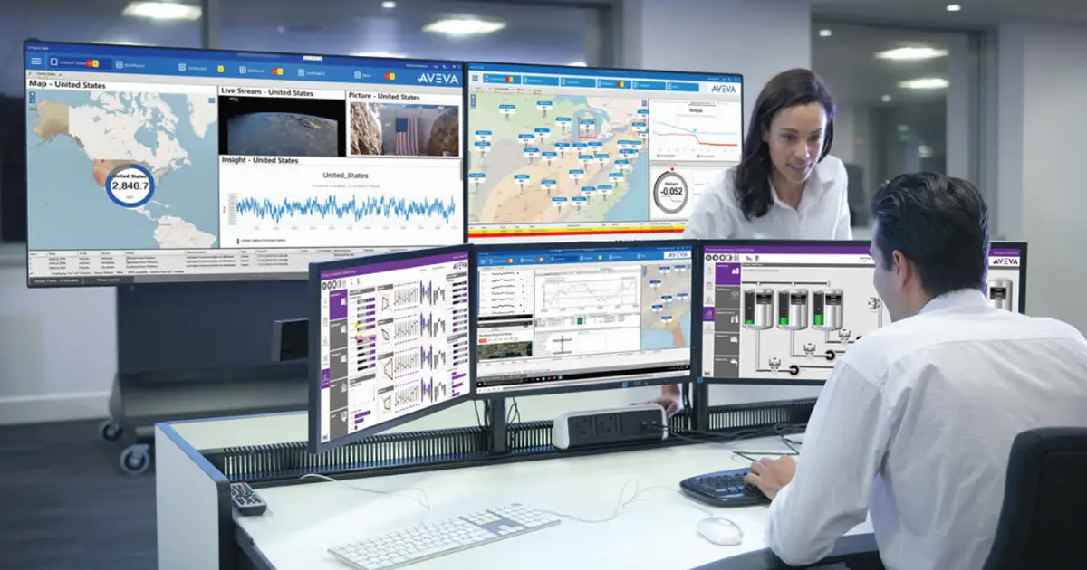 two workers looking at computer screens full of data